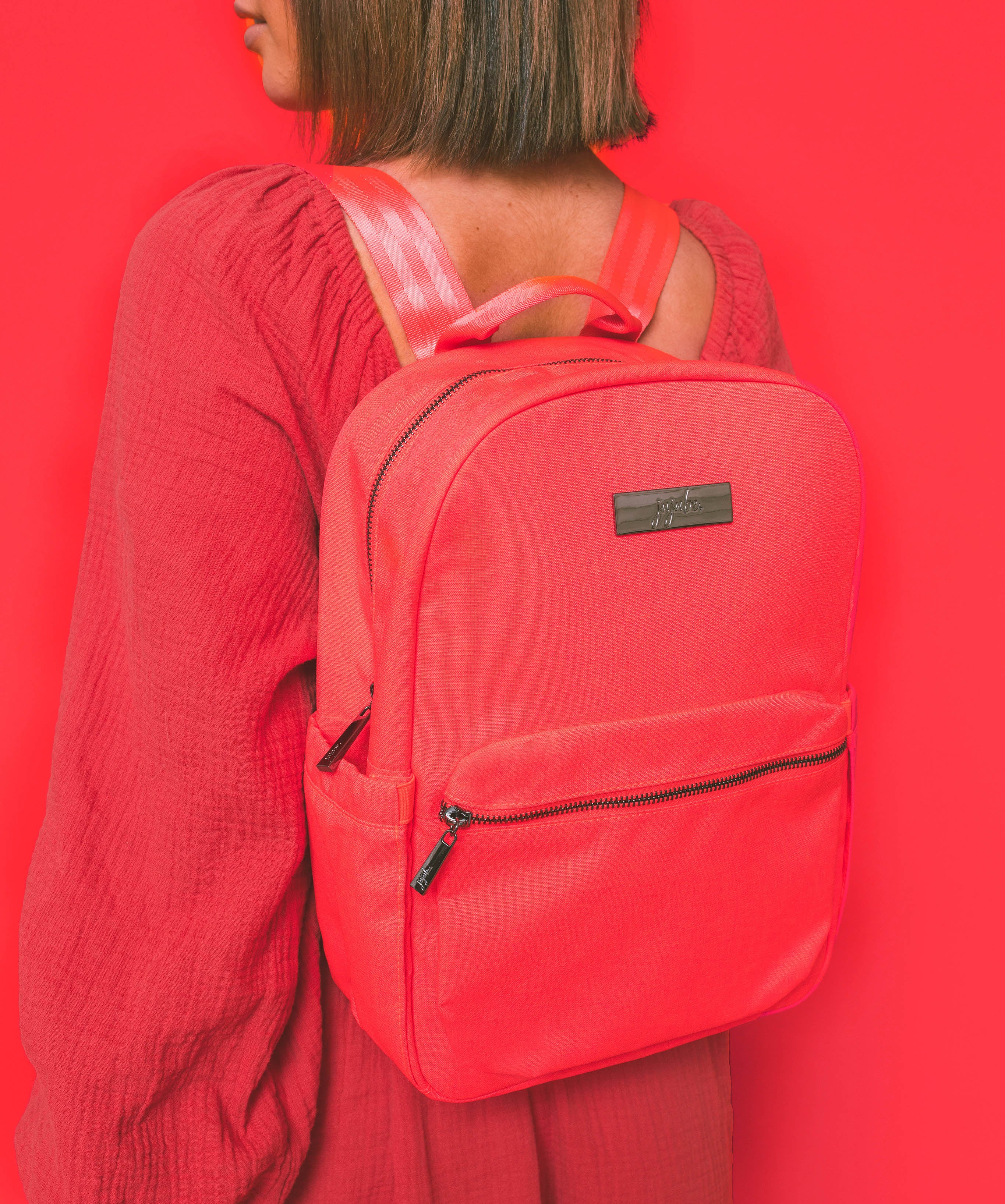 Neon Coral Pink Midi Backpack Worn by Woman wearing a matching color dress