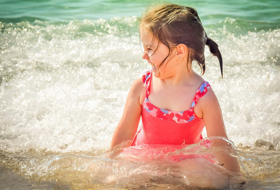 Little girl giggles while sitting in ocean waves