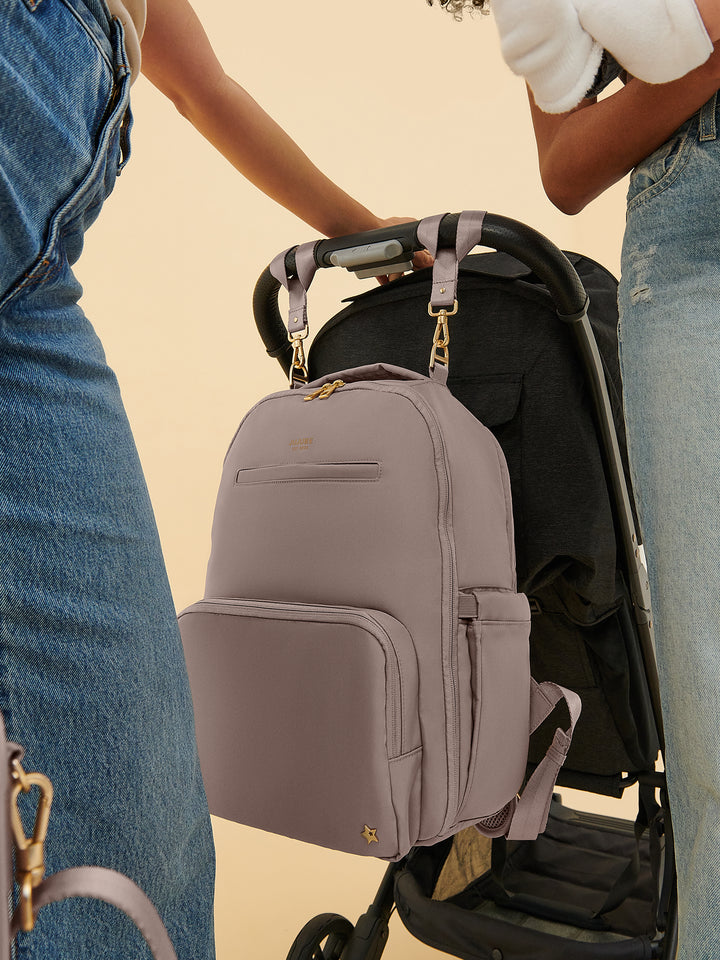 JuJuBe Classic Diaper Backpack in Taupe attached to a stroller using the trolley sleeve
