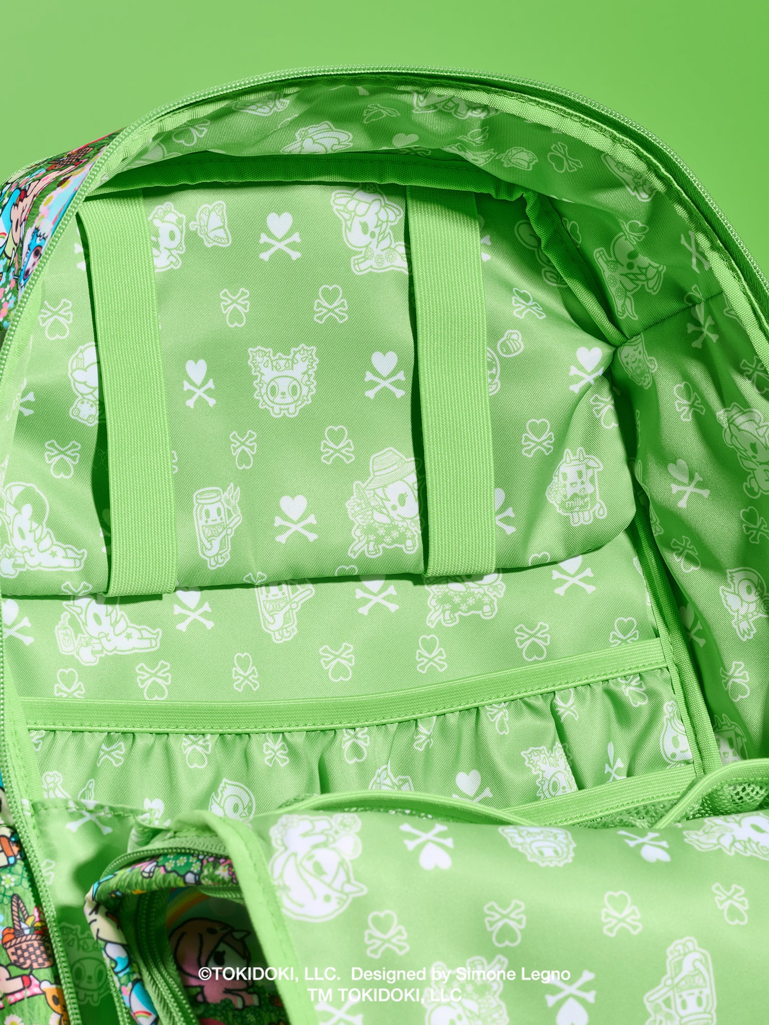 tokidoki x JuJuBe Zealous Diaper Bag Backpack in Meadow Blooms – interior view of the open main compartment showing green tokidoki print lining and slip pockets