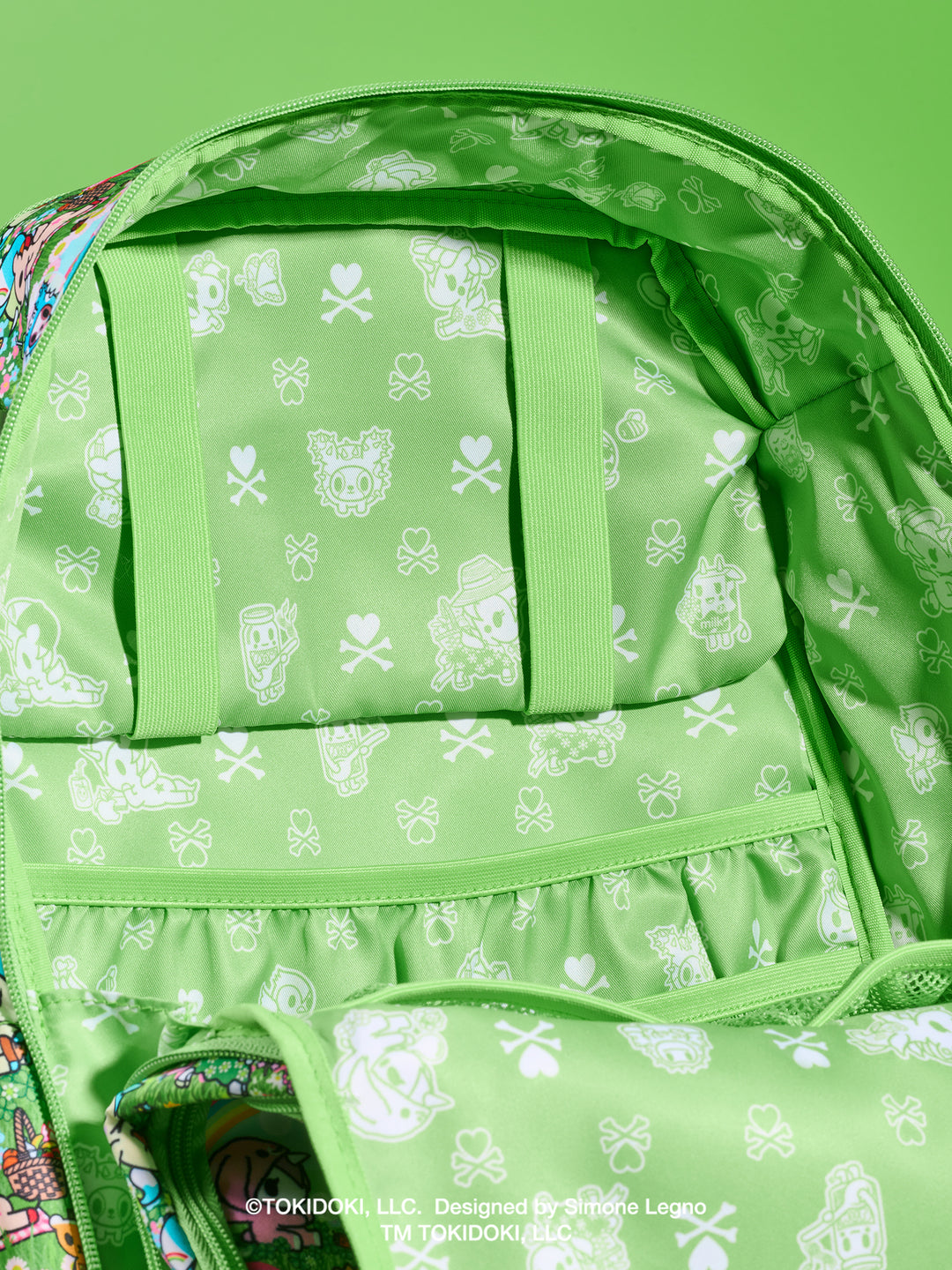 tokidoki x JuJuBe Zealous Diaper Bag Backpack in Meadow Blooms – interior view of the open main compartment showing green tokidoki print lining and slip pockets