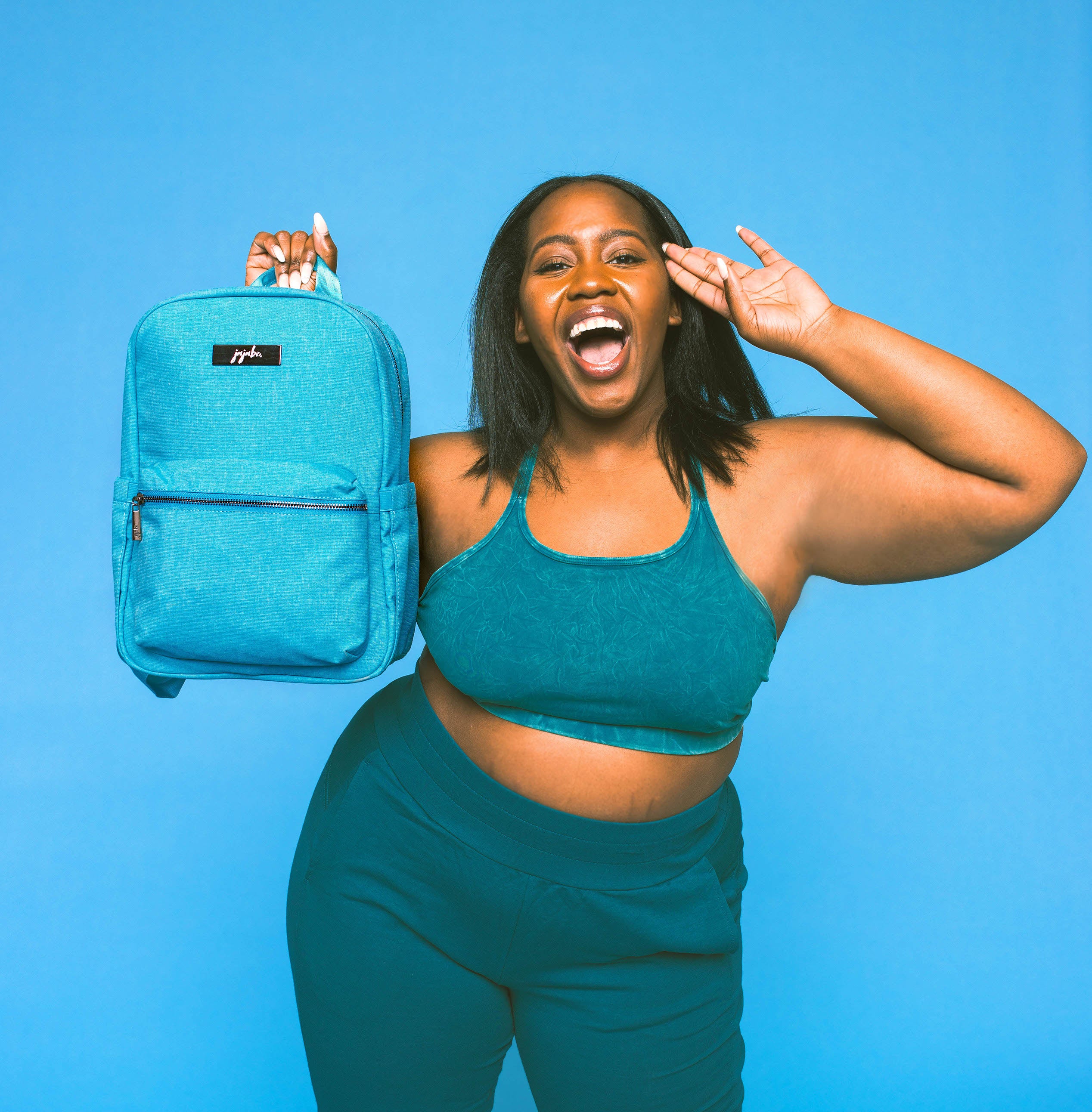 Bright Blue Midi Backpack Held by woman wearing matching colored workout gear