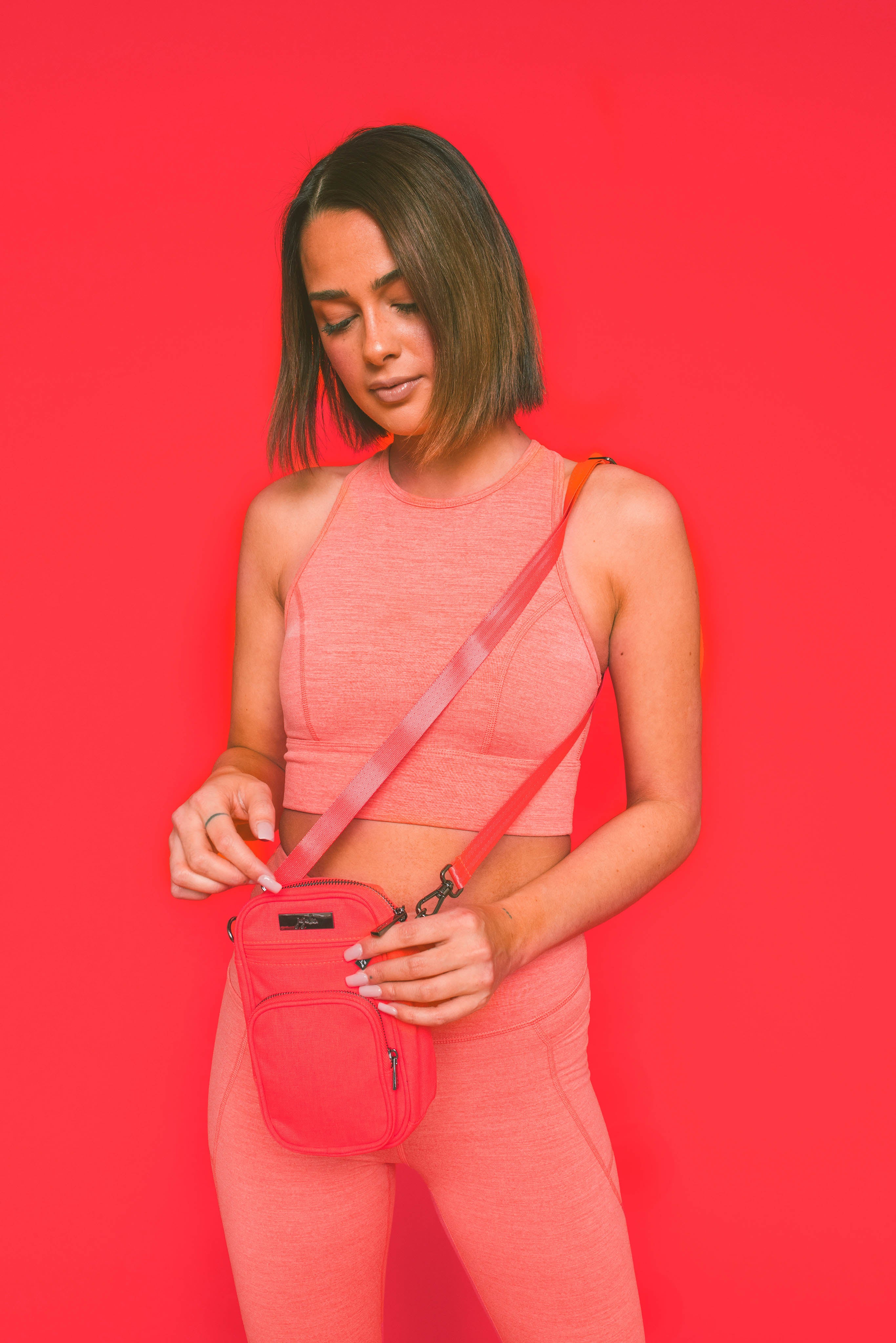 Neon Coral Pink Mini Helix Crossbody Bag Worn by Woman Wearing Matching Working Wear